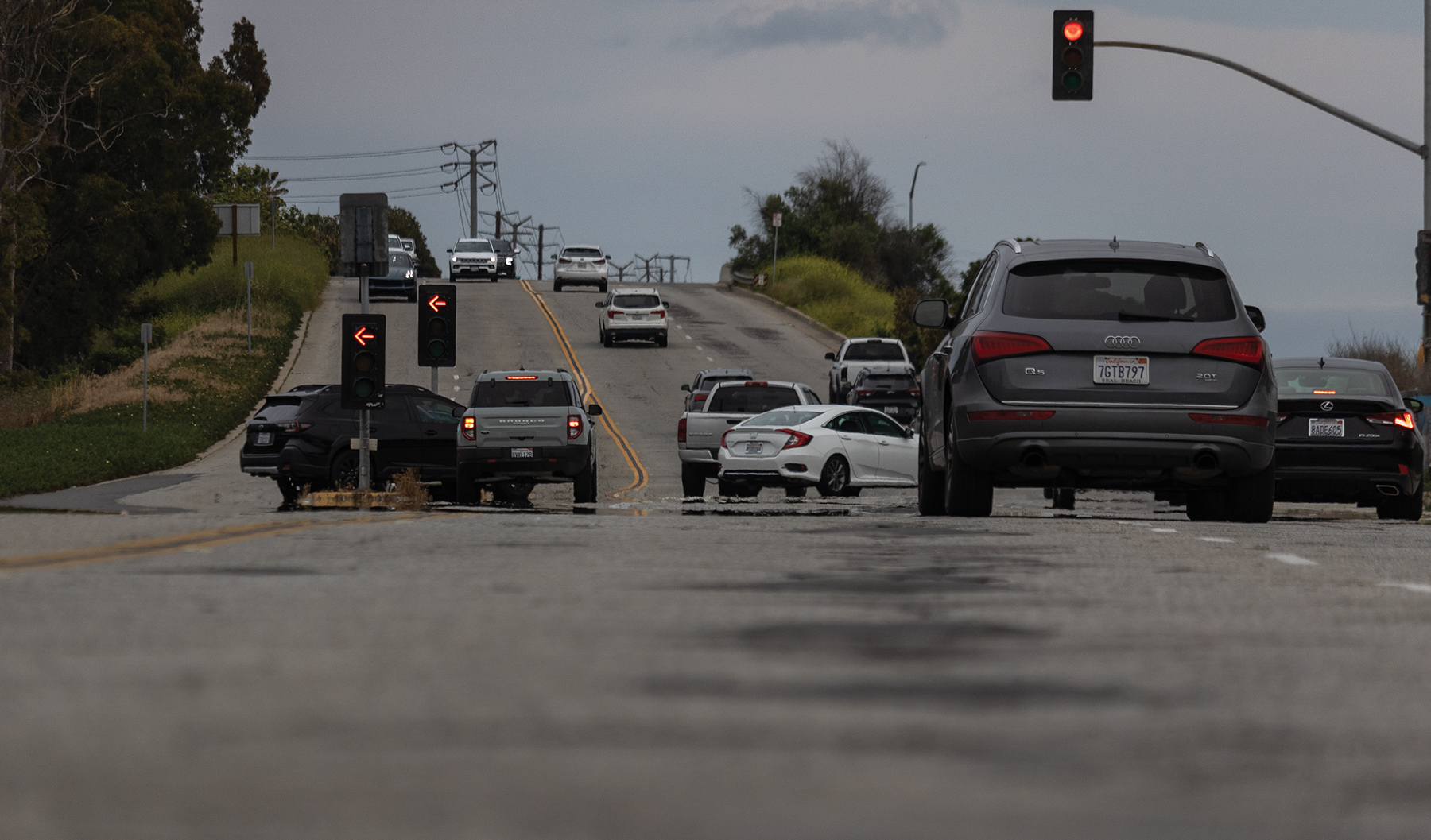 Cars drive along a road that needs a lot of work.
