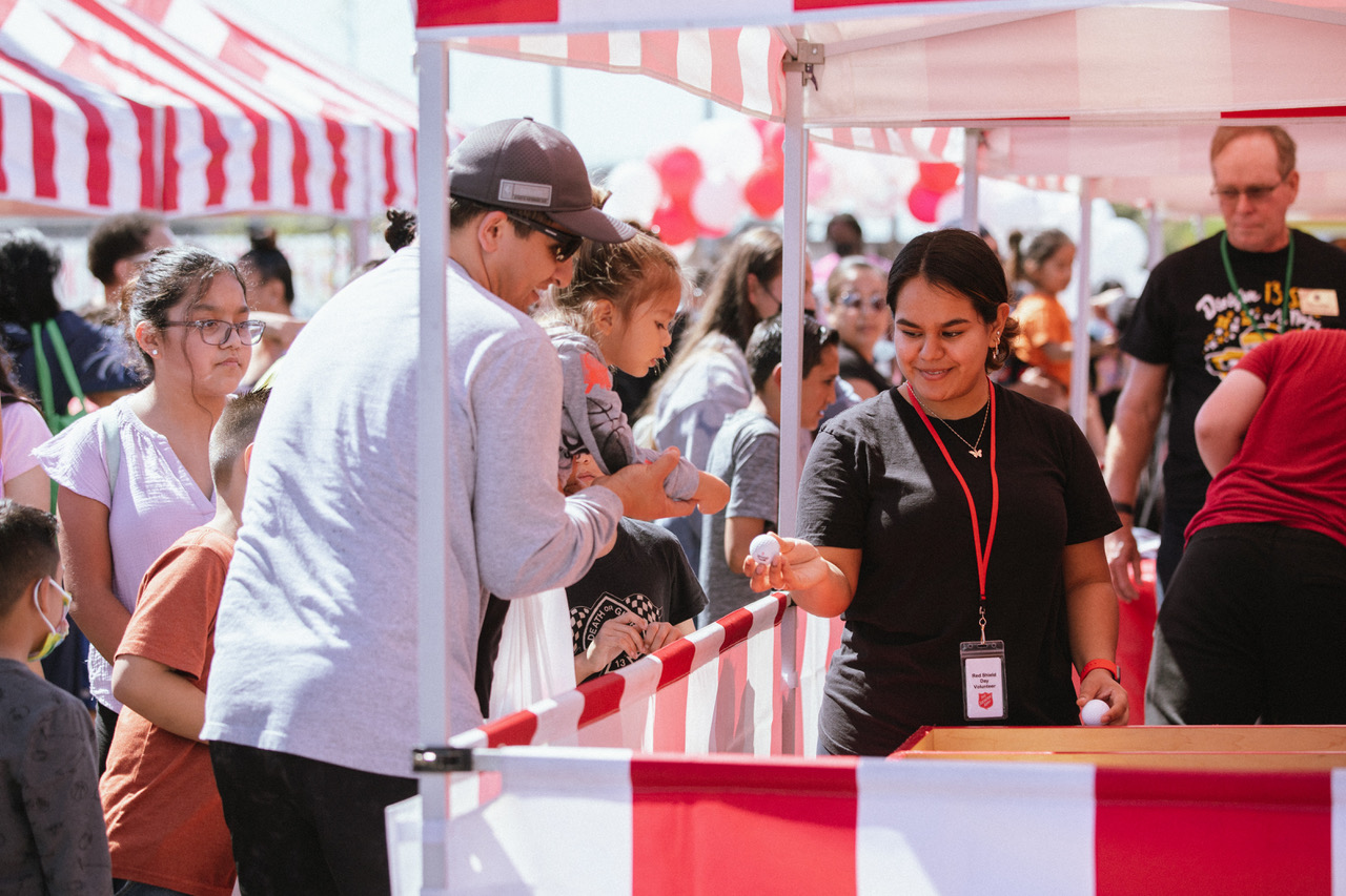 A man plays a game at a carnival booth decorated with red and white stripes.