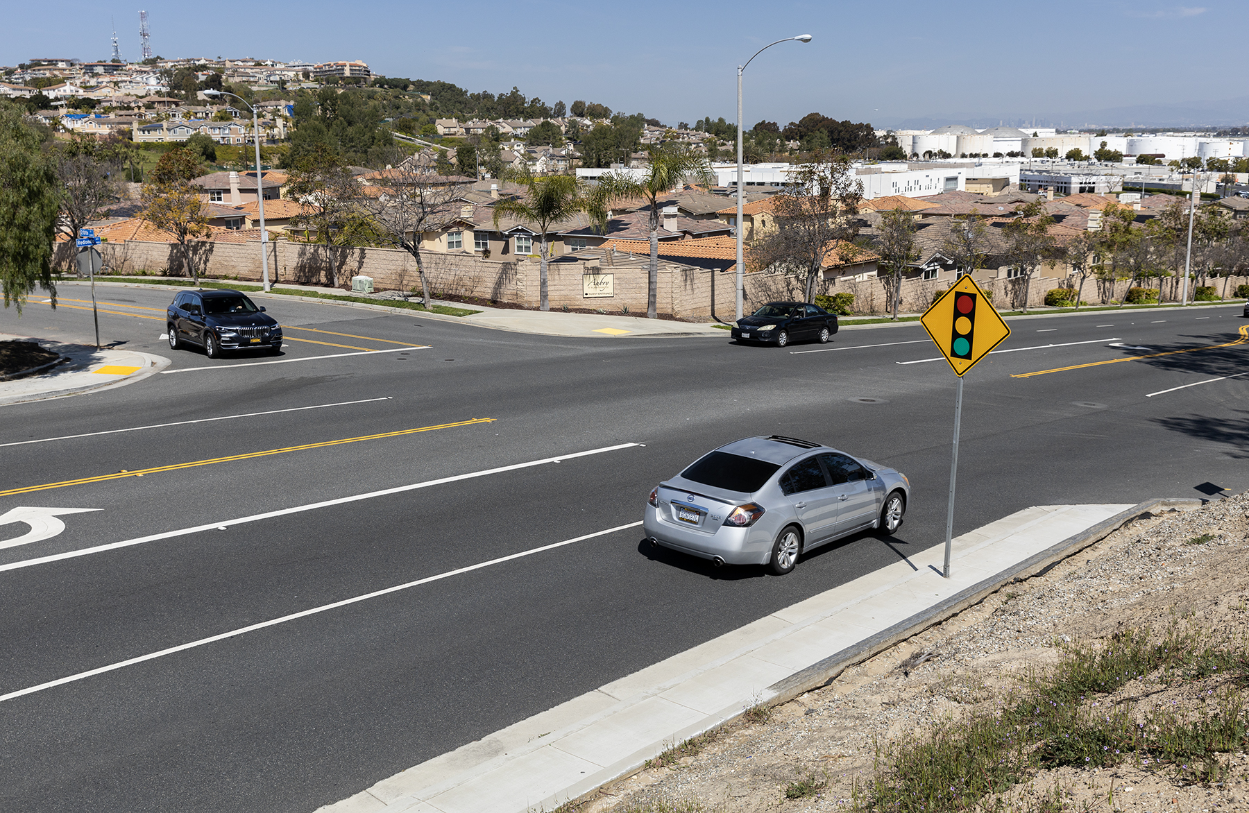 Three cars are driving at a four-way intersection.