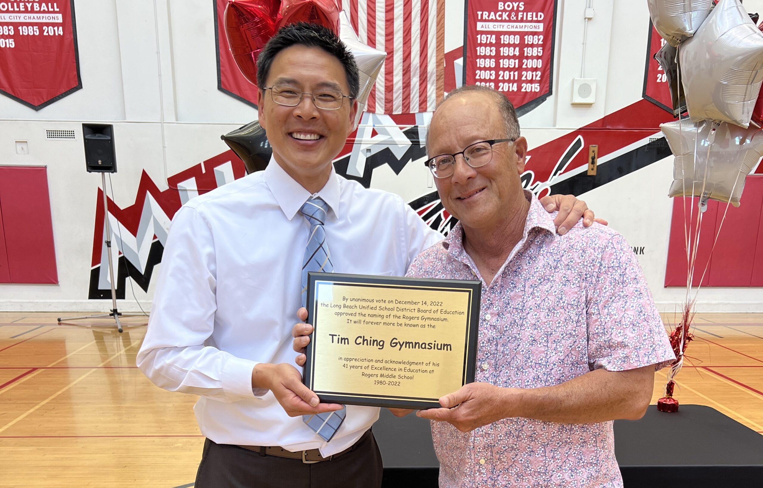 Two men hold a plaque between them.