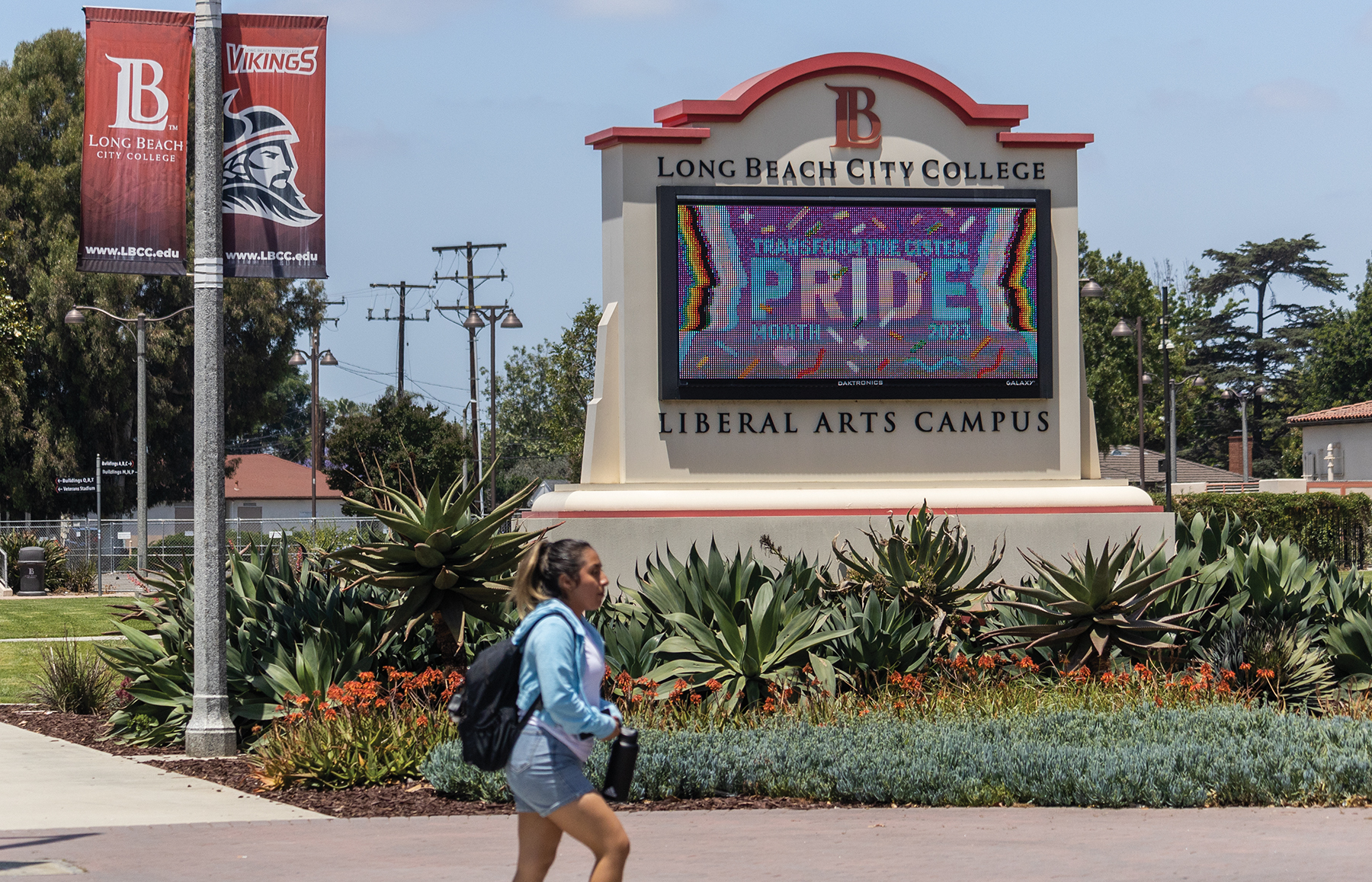 A young woman walks in front of a sign for Long Beach City College's Liberal Arts Campus.