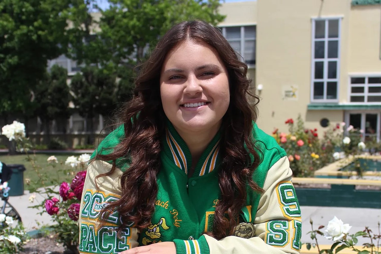 A woman in a letterman jacket smiles at the camera.