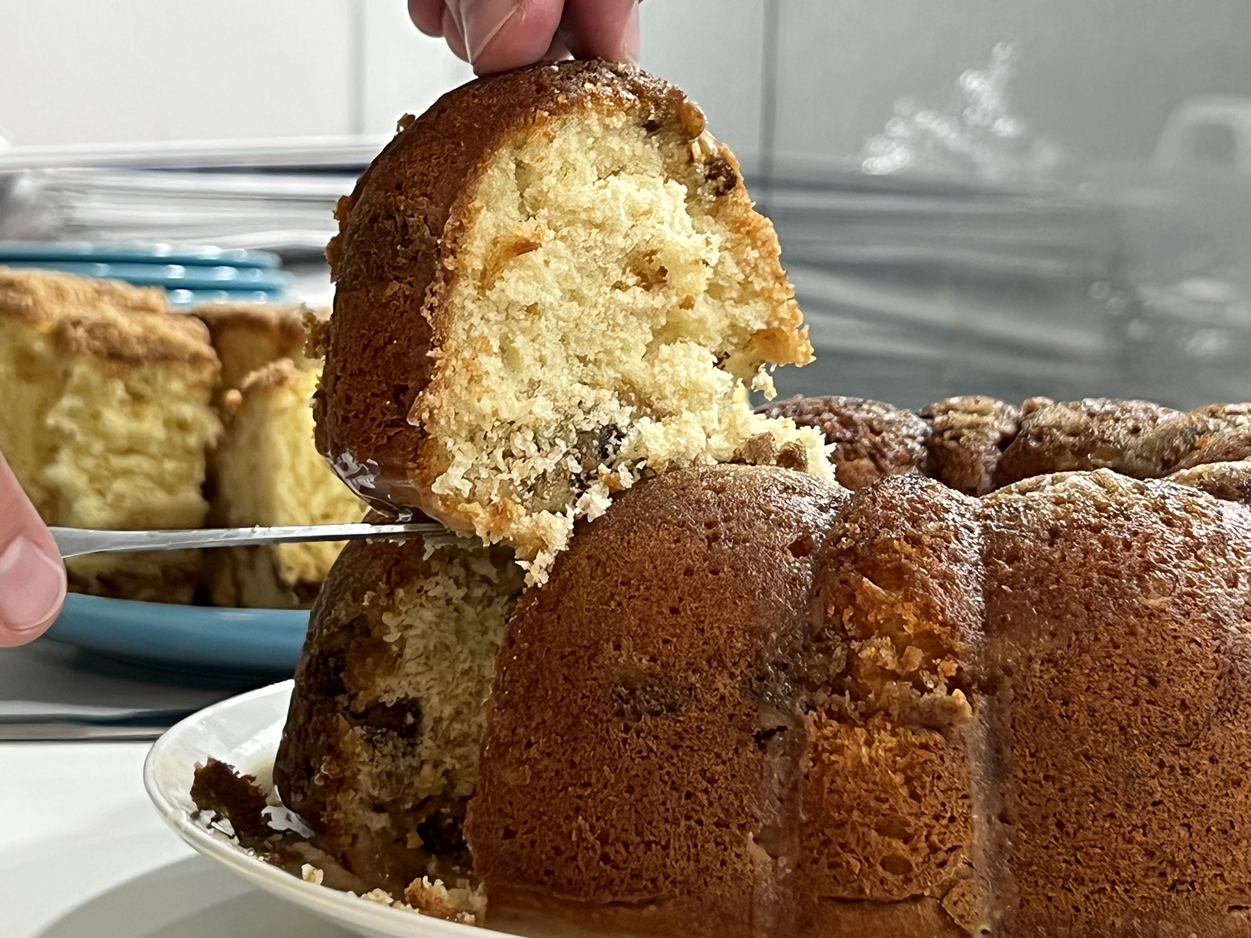 A Bundt-style coffee cake sits on a table and is cut.
