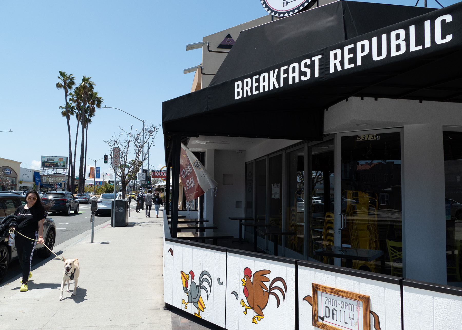 A woman walks her dog past Breakfast Republic on Second Street in Belmont Shore.