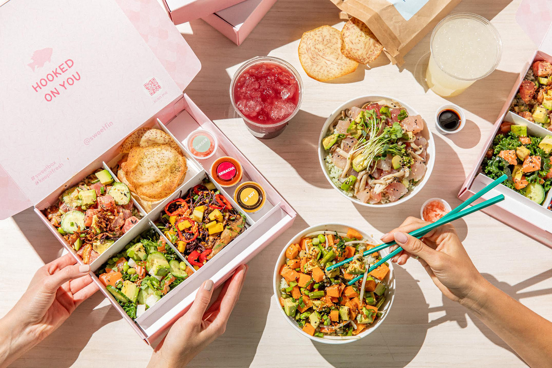 A bento box and poke bowls are displayed on a table at Sweetfin. 